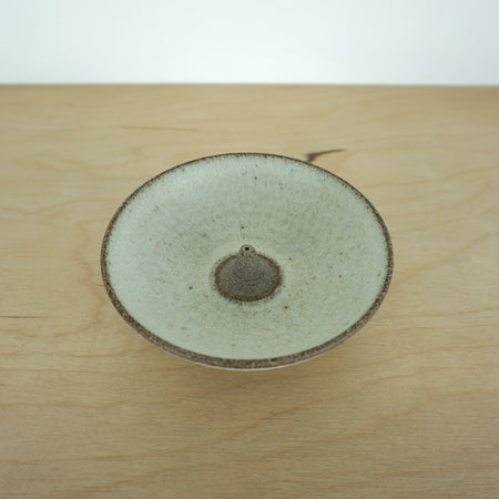 close up image of an ivory coloured incense holder on a wooden table. 