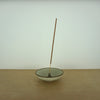 a simple and elegant incense holder with a stick of incense on a table. 