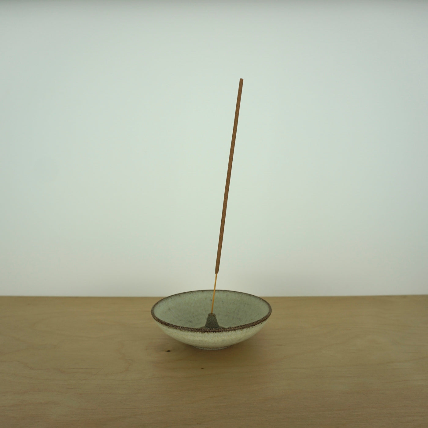 a simple and elegant incense holder with a stick of incense on a table. 