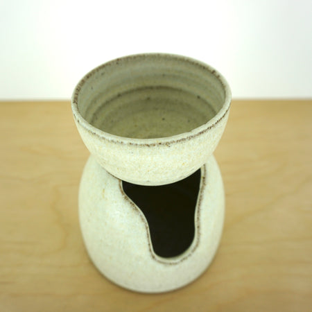 white handmade oil burner sitting on a birch ply table with a white background.