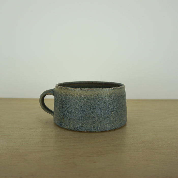 elegant handmade ceramic mug on a wooden table with a white background. 