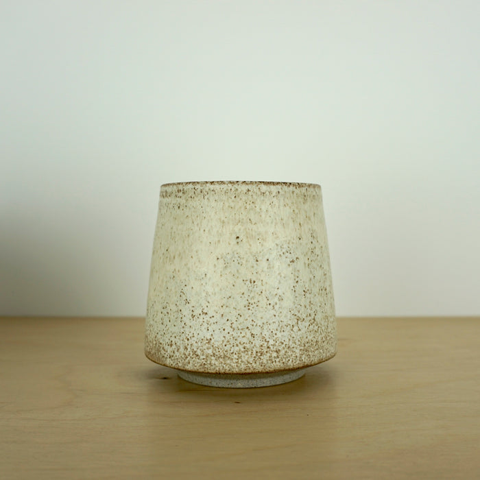 an ivory Yunomi cup on a wooden table. 