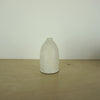 a small ivory coloured white handmade ceramic vase on a table. 