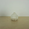 a small ivory coloured white handmade ceramic vase on a table. 