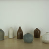 a group of small individual vases sitting on a wooden table. 