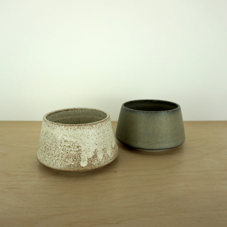 two angular tea bowls on a wooden table. 