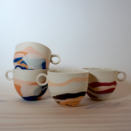 group of four marbled porcelain mugs on a table. 