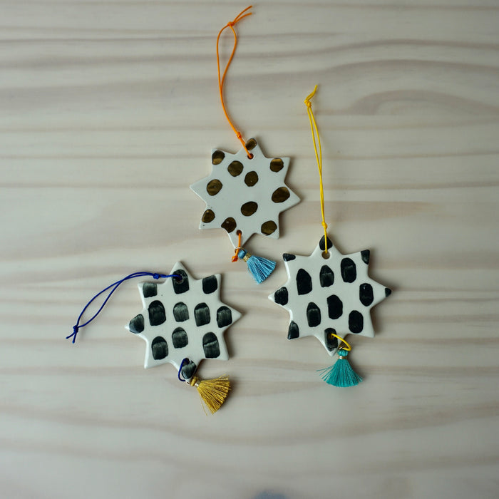 three handmade ceramic Christmas decoration by Beci Callow with black & gold spots and colourful tassel. 