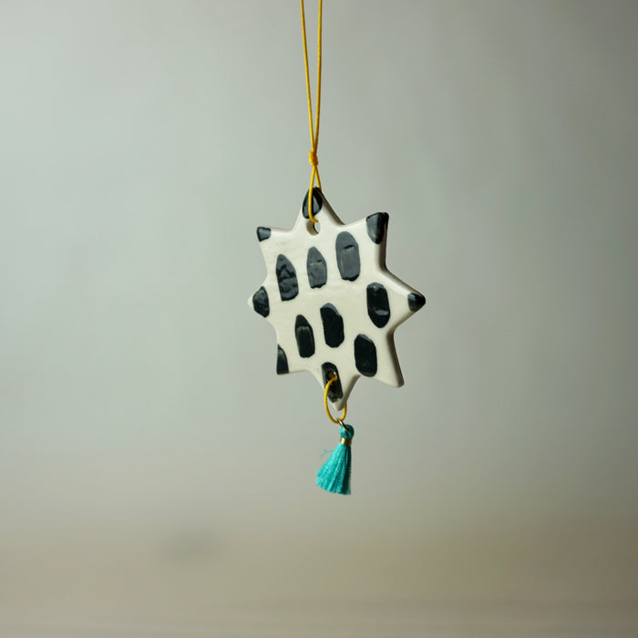 handmade ceramic Christmas decoration by Beci Callow with black spots and colourful tassel. 