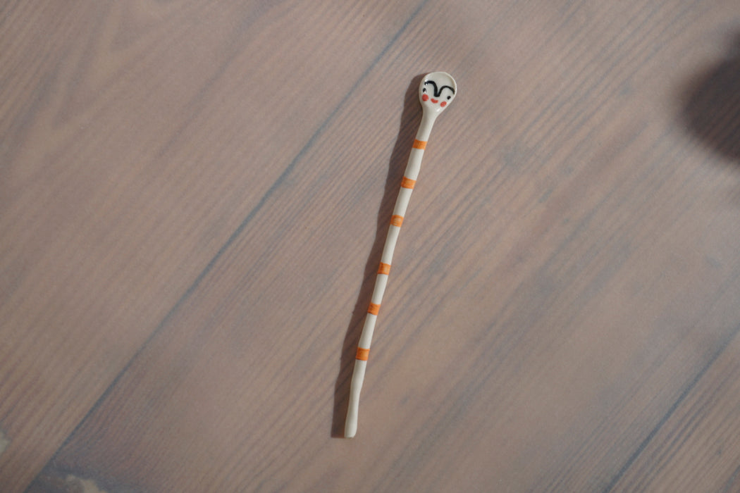 a striped orange porcelain salt spoon lying on a table