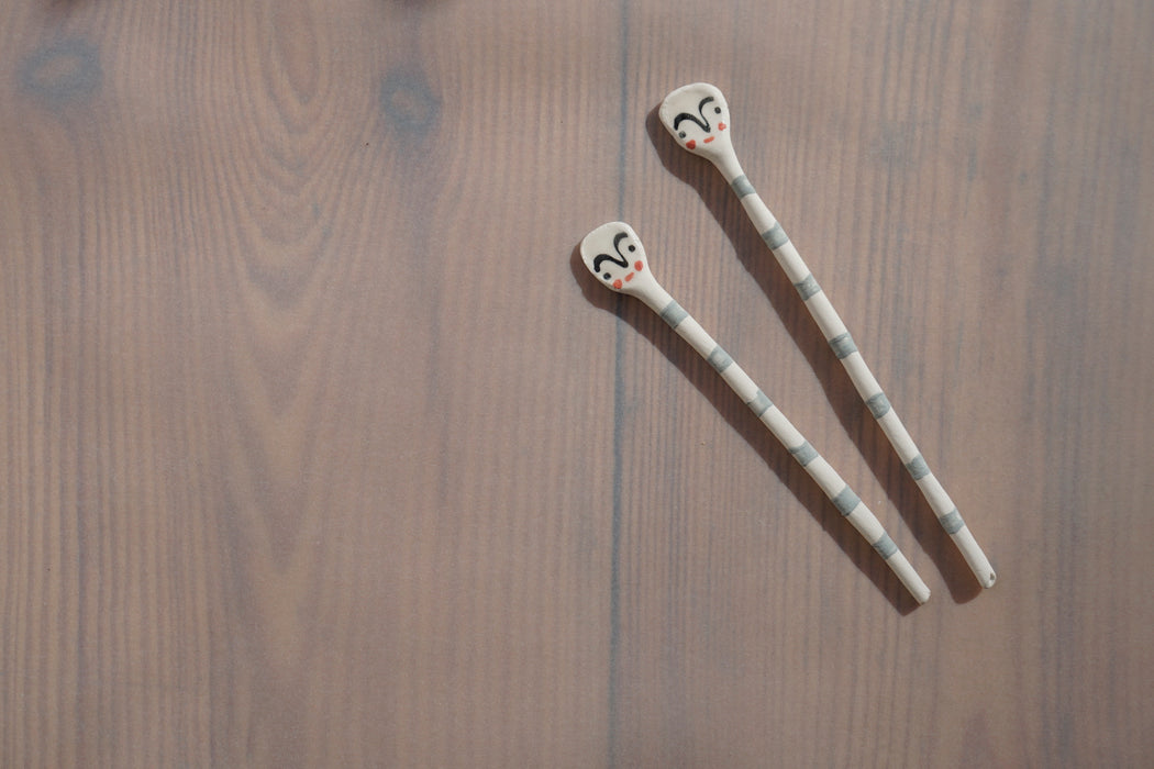 tiny salt spoons with blue stripes and faces hand painted on the end. 