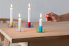 Four glass candlestick holders sitting on a table being lit. 