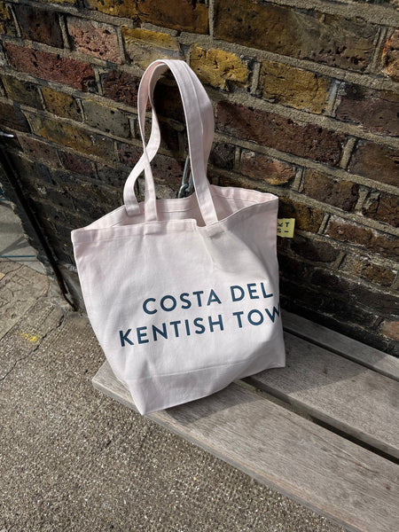 a pink beach bag sitting on a wooden bench. 