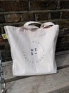 a pink beach bag on a wooden bench with the logo of Kentish Town stores. 