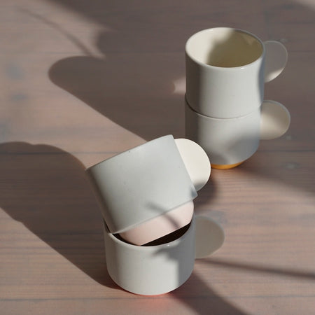 stacking porcelain espresso cups in two piles of two. blue cups with white half moon handles. 