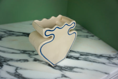 cream vase with blue outline pattern on a marble worktop