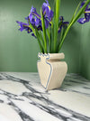 side view of a cream vase with blue outline pattern and a bunch of iris on a green background