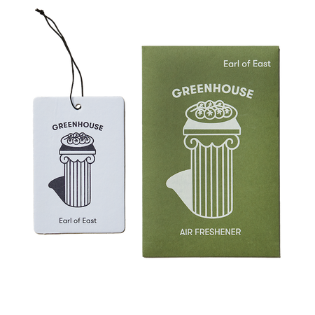 Earl of East Air Freshener tag next to the green packet. a drawing of a pillar in white on green with a bowl of tomatoes on it. its called greenhouse. 