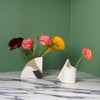 two bud vases side by side on a marble table. 