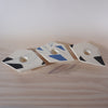 three abstract, angular candlestick holders in a line on a wooden table. 
