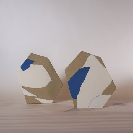 two handmade porcelain vases that are inspired by architectural forms sitting on a table. 