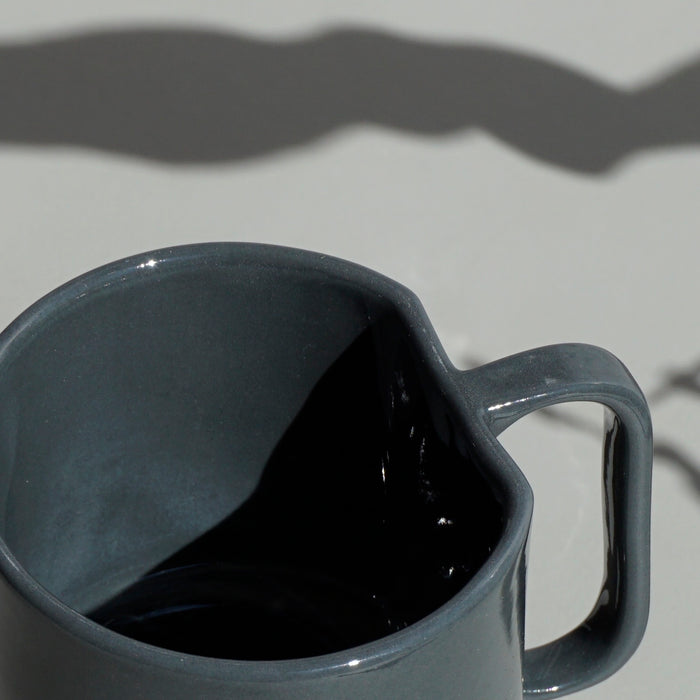 close up detail of a dark grey slipcast mug with an angular handle by emma johnson ceramics. 