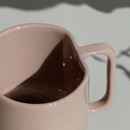 close up detail of a dusty pink slipcast mug with an angular handle by emma johnson ceramics. 