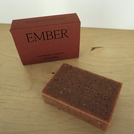 a bar of soap lying on a table and a box for the soap standing up with the word Ember on it. 