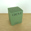 Evermore London candle box on a wooden table. the box is green with black lettering that says grove. 