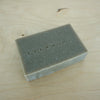 a bar of blue grey soap lying on a table with the brand name Evermore embossed in the soap. 