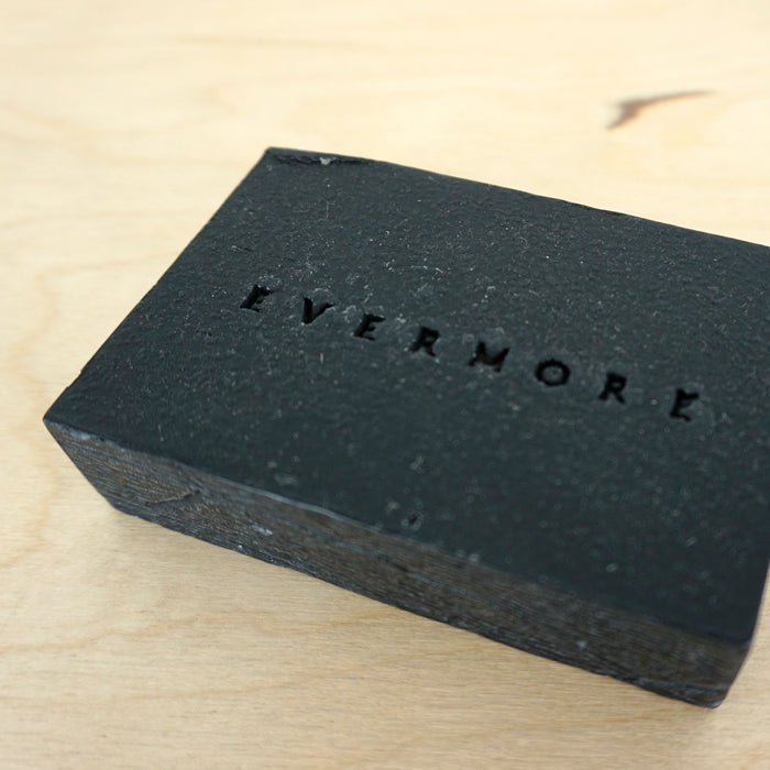 an activated charcoal soap on a table with the word Evermore imprinted on the soap. 