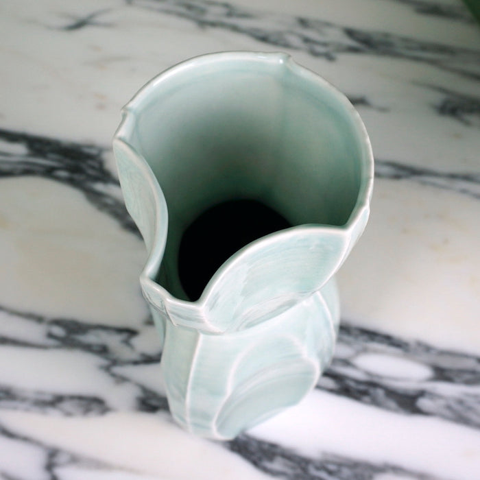 the top view of a green handmade ceramic vase on a marble table. 