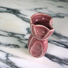 the side view of a red vase on a marble table. 