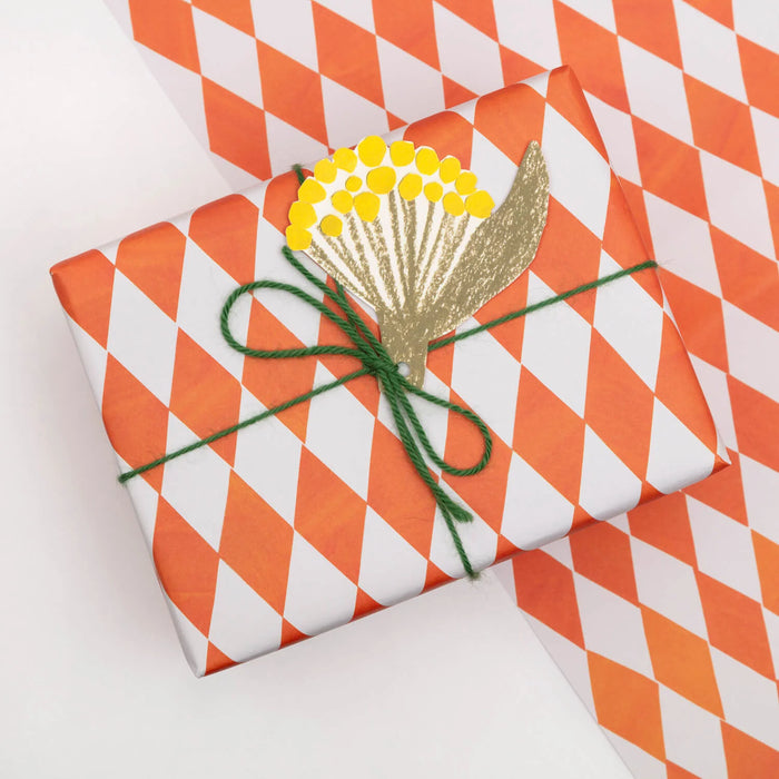 a present wrapped in geometric orange and white gift wrap on a white background by Hadley Paper Goods. 