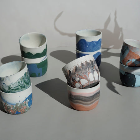 five pairs of marbled coffee cups on a blue table. 