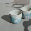 two handmade porcelain marbled espresso cups on a table in the sunshine. 