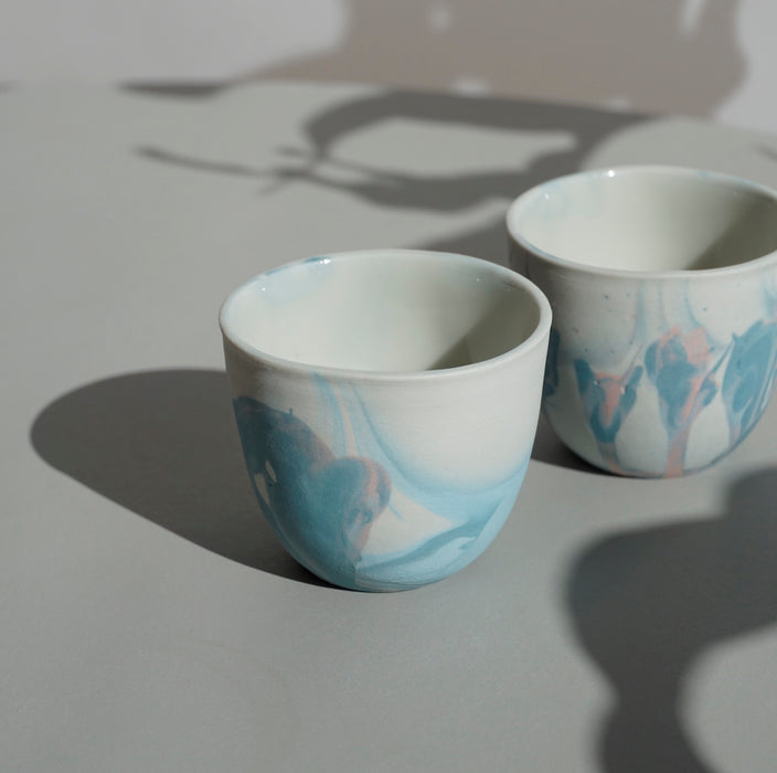 two handmade porcelain marbled espresso cups on a table in the sunshine. 