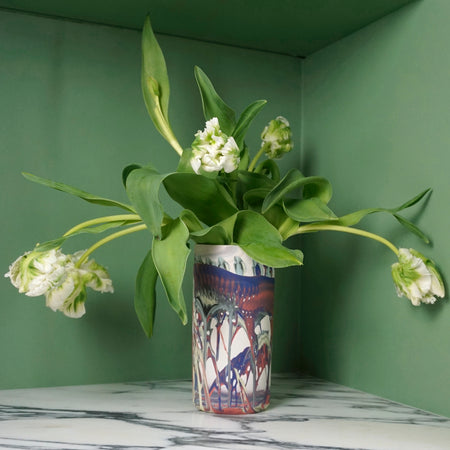 bunch of poppies in a large marble porcelain handmade case on a marble table with a green background. 