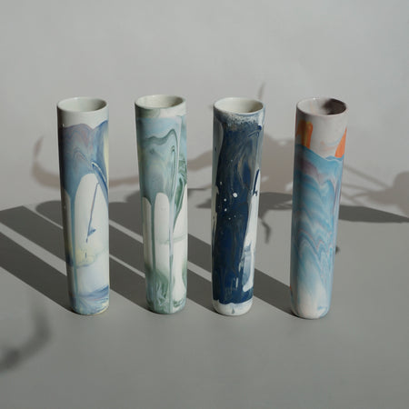 four tall handmade bud vases in a line with a marble pattern. 