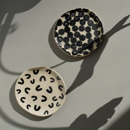 two flat handmade ceramic dishes on a table in the sunshine. 