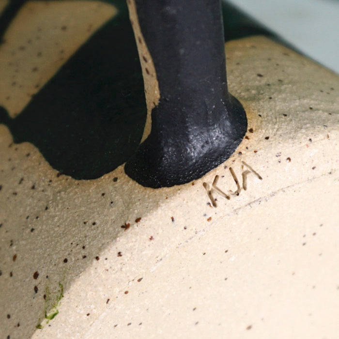 the maker mark of KJA ceramics in the base of a black splatter jug handle. 