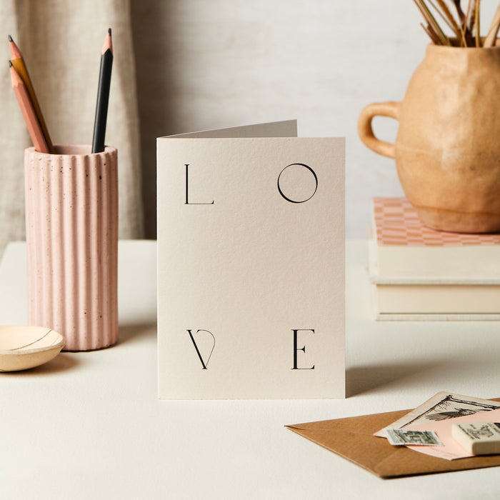 a pink card with a letter in each corner spelling L O V E 