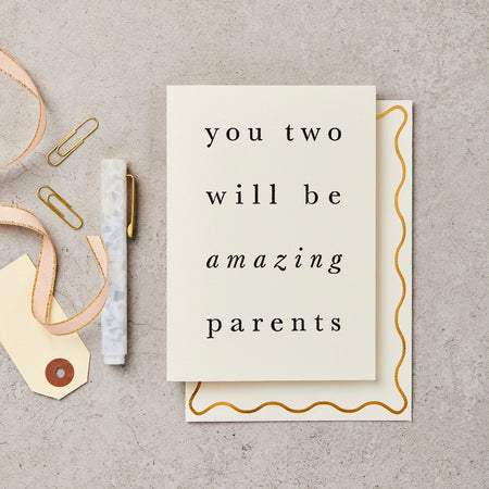 a card for new parents with a ribbon on a table. 