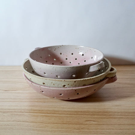 stack of handmade mae ceramics Colanders in pink and chalk. 