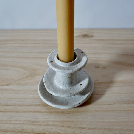 Close up detail of white handmade candlestick holder by Mae Ceramics with a Beeswax candle. 