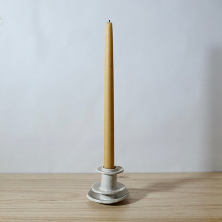 white handmade candlestick holder by Mae Ceramics with a Beeswax candle. 