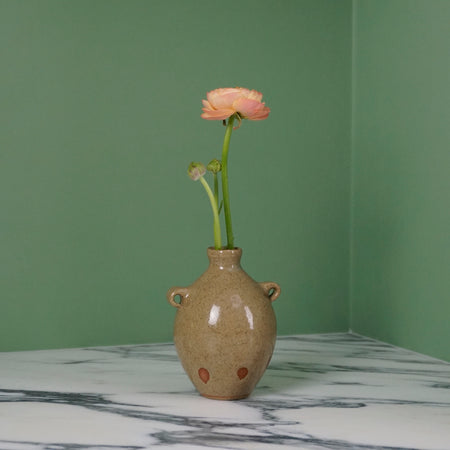 handmade ceramic bud vase in a Oat glaze with a flower. 