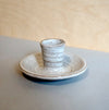 a candle stick holder on a light blue table with a tin white glaze. 