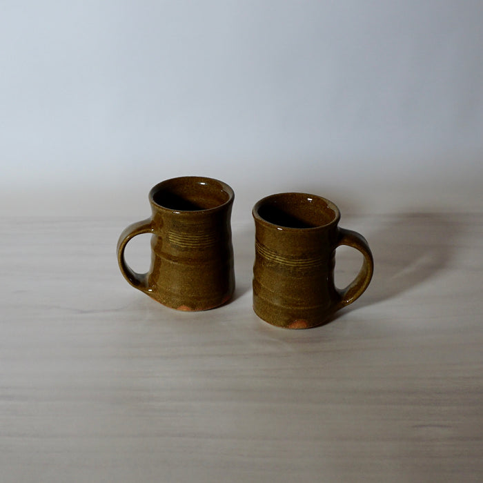 two espresso cups in a nicotine glaze on a pale background. 