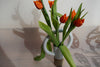 a straight vase with an oversized round handle at the top. and a bunch or red tulips